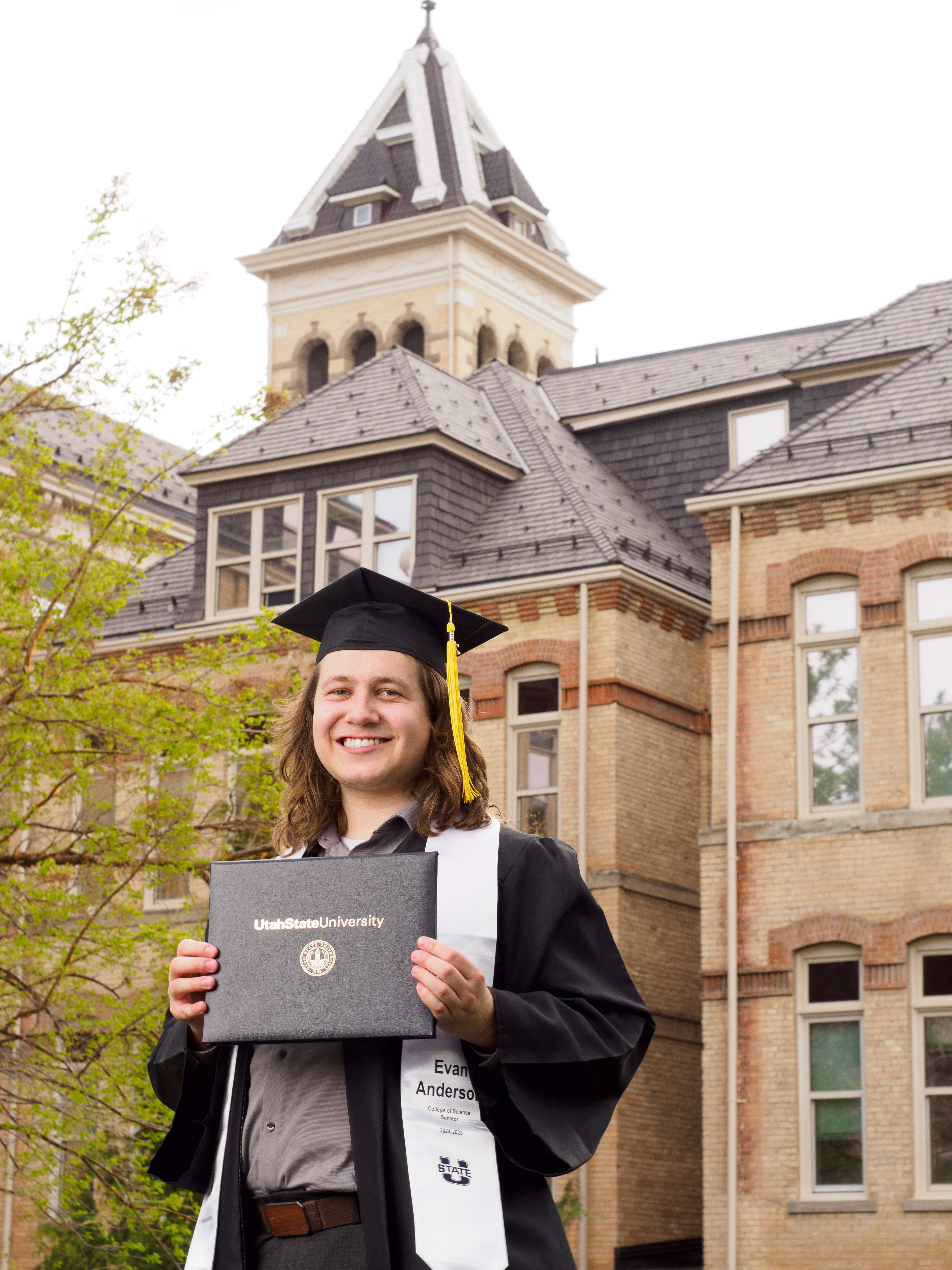 Evan Anderson holding Utah State University diploma